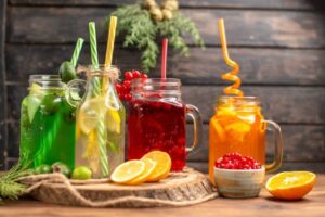 front-close-view-organic-fresh-juices-bottles-served-with-tubes-fruits-wooden-cutting-board-brown-table_140725-94487